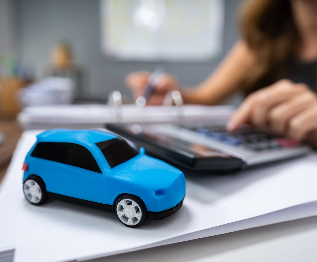 Toy car on financial paperwork while reviewing auto loan protection costs
