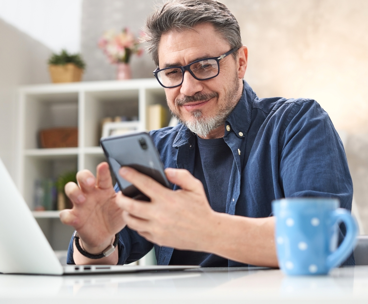 Man using a smartphone and laptop to connect with credit union services