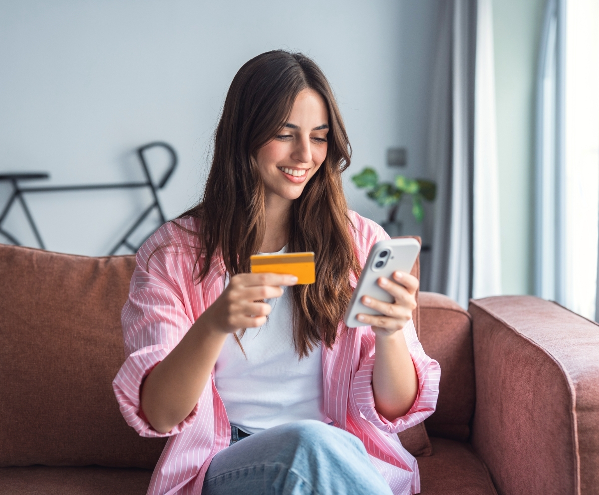 Woman using a smartphone and debit card to access member banking services