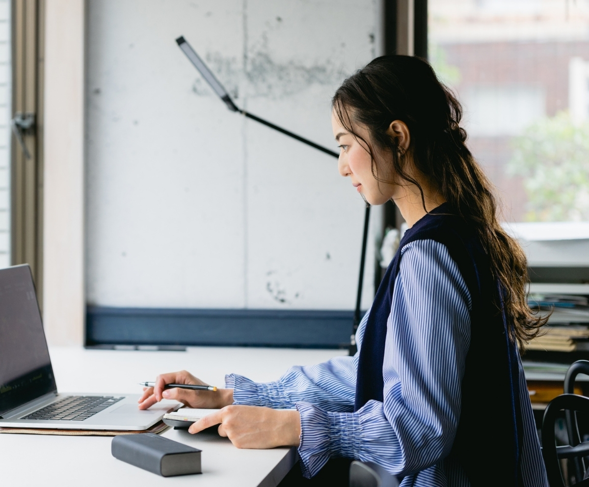 Woman using a laptop and calculator to organize debt repayment options